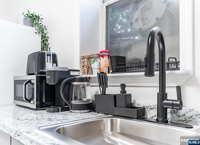 room details featuring light stone countertops and sink