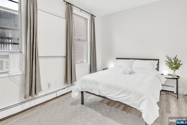 bedroom featuring light hardwood / wood-style floors and a baseboard heating unit