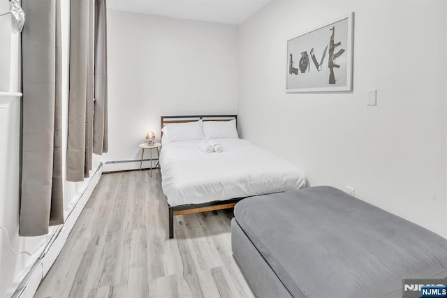 bedroom featuring baseboard heating and light hardwood / wood-style flooring