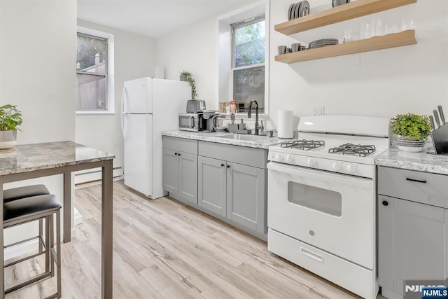 kitchen featuring sink, white appliances, gray cabinets, and light stone countertops