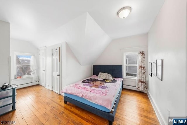 bedroom with hardwood / wood-style flooring, lofted ceiling, and a baseboard heating unit