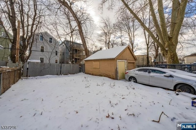 yard covered in snow featuring an outbuilding and a garage