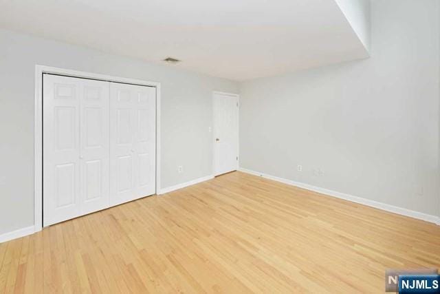 unfurnished bedroom featuring a closet, baseboards, and wood finished floors