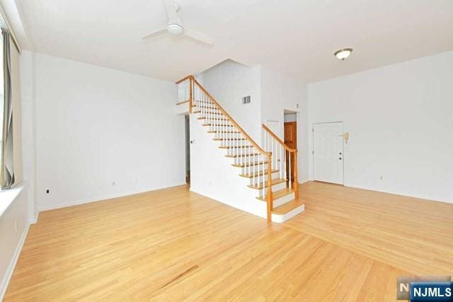 unfurnished living room featuring stairs, ceiling fan, wood finished floors, and visible vents