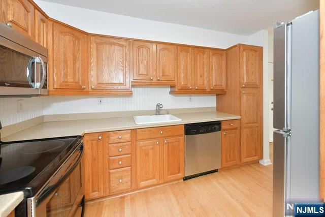 kitchen with stainless steel appliances, light countertops, and a sink