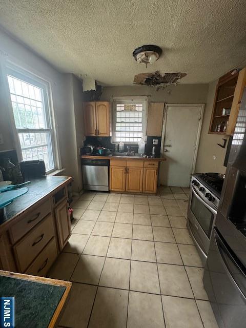 kitchen featuring light tile patterned flooring, sink, backsplash, stainless steel appliances, and a textured ceiling