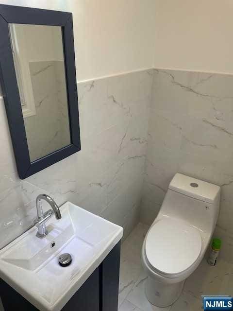 bathroom featuring tile walls, vanity, and toilet