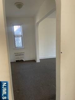 interior space featuring arched walkways and radiator heating unit