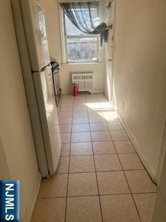 interior space featuring radiator heating unit and light tile patterned flooring