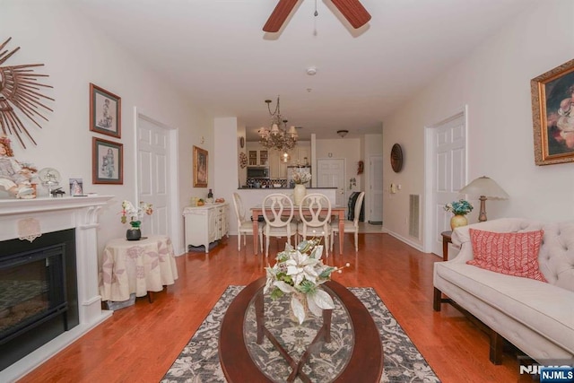 living room with hardwood / wood-style flooring and ceiling fan with notable chandelier