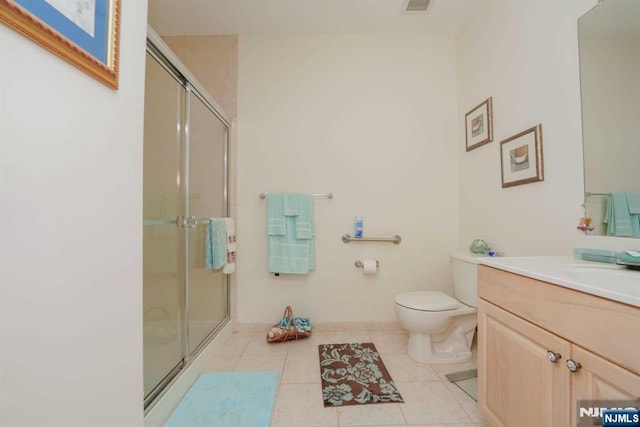 bathroom with tile patterned flooring, vanity, toilet, and walk in shower