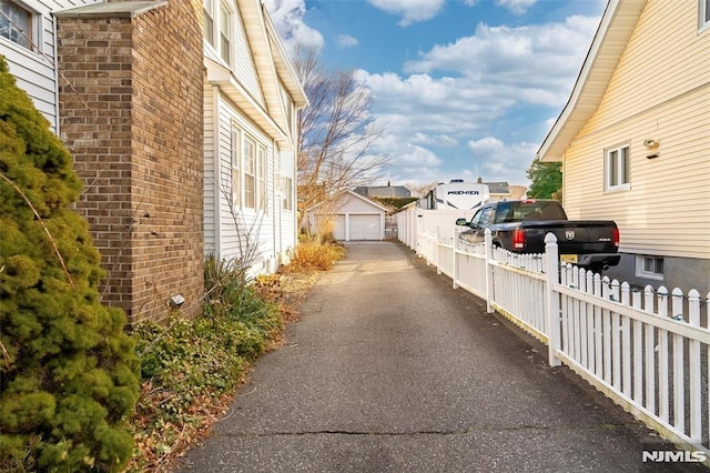 view of property exterior featuring an outbuilding, brick siding, a detached garage, fence, and a residential view