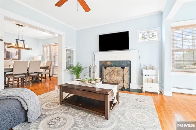 bedroom featuring ornamental molding, multiple windows, a baseboard radiator, and light wood-style floors