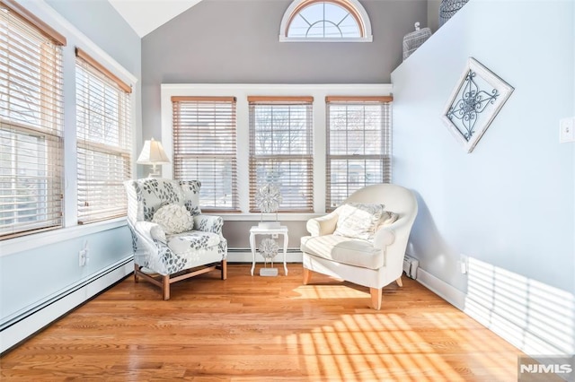 living area featuring a baseboard heating unit, lofted ceiling, and a healthy amount of sunlight