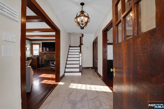 entryway featuring a brick fireplace, a chandelier, and beam ceiling