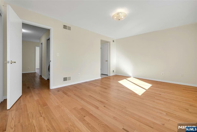 unfurnished room with light wood finished floors, baseboards, and visible vents