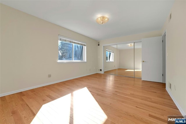 unfurnished bedroom featuring light wood finished floors, a closet, visible vents, and baseboards