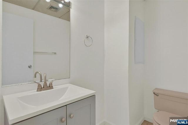 bathroom with toilet, baseboards, visible vents, and vanity