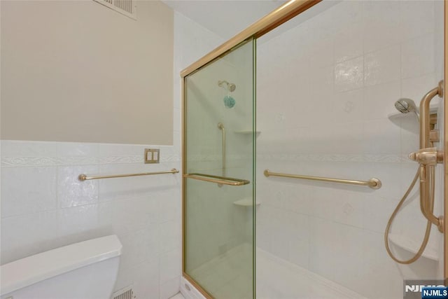 full bath with a stall shower, visible vents, tile walls, and toilet