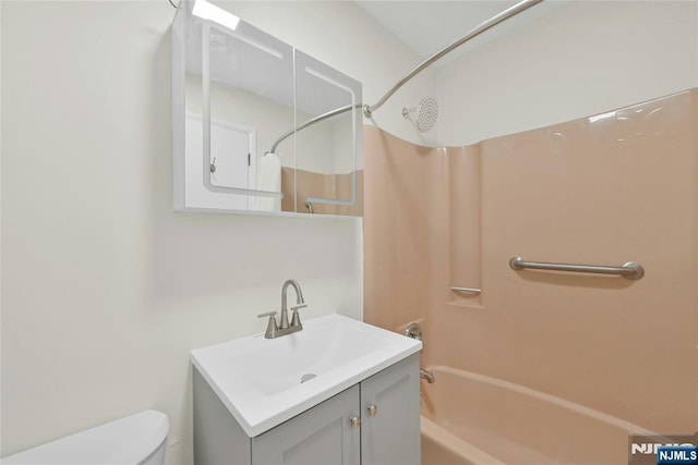 bathroom with washtub / shower combination, vanity, and toilet