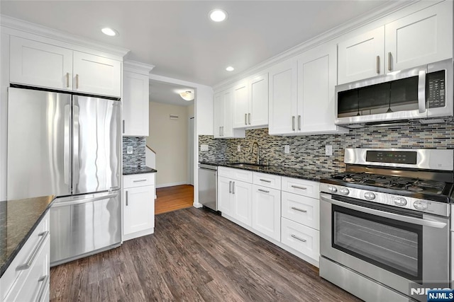 kitchen featuring white cabinets, dark stone counters, stainless steel appliances, and a sink