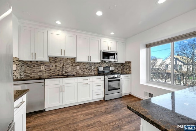 kitchen featuring stainless steel appliances, dark stone counters, white cabinets, and visible vents