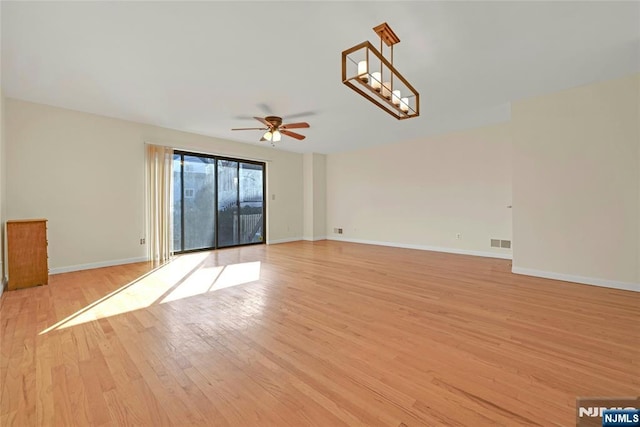 spare room featuring light wood-style floors, visible vents, baseboards, and a ceiling fan