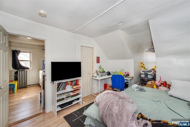 bedroom featuring radiator, vaulted ceiling, and light hardwood / wood-style flooring