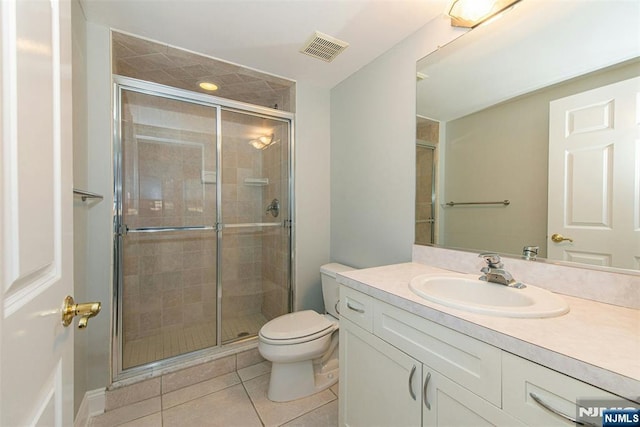 bathroom featuring tile patterned floors, toilet, vanity, and a shower with shower door