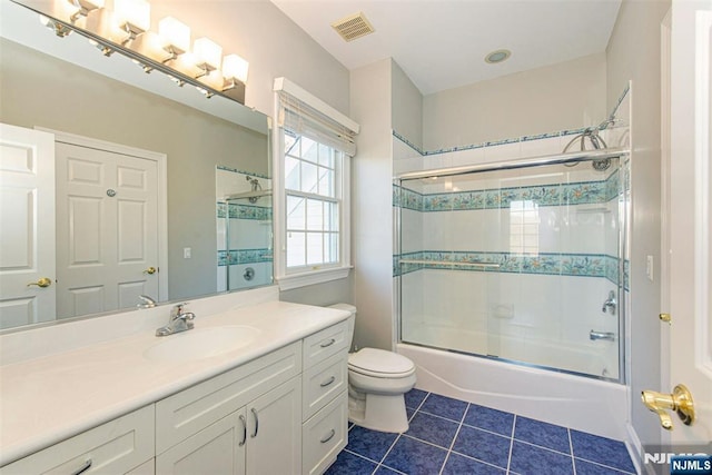 full bathroom featuring tile patterned floors, bath / shower combo with glass door, toilet, and vanity