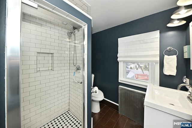 full bath featuring a stall shower, wood finish floors, baseboards, and toilet