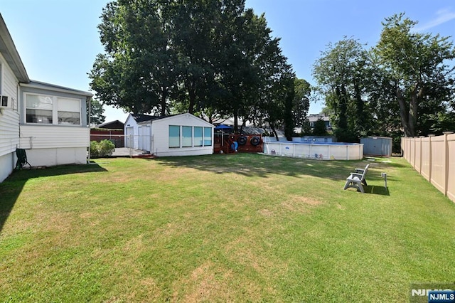 view of yard with a storage unit, an outdoor structure, a fenced backyard, and a fenced in pool