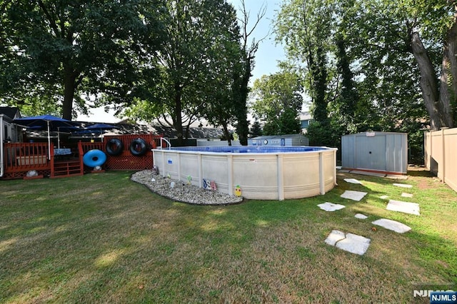 view of yard featuring a fenced in pool, an outbuilding, a deck, a shed, and a fenced backyard