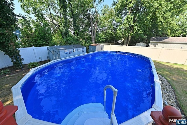 view of swimming pool with a shed, a fenced in pool, a fenced backyard, and an outbuilding