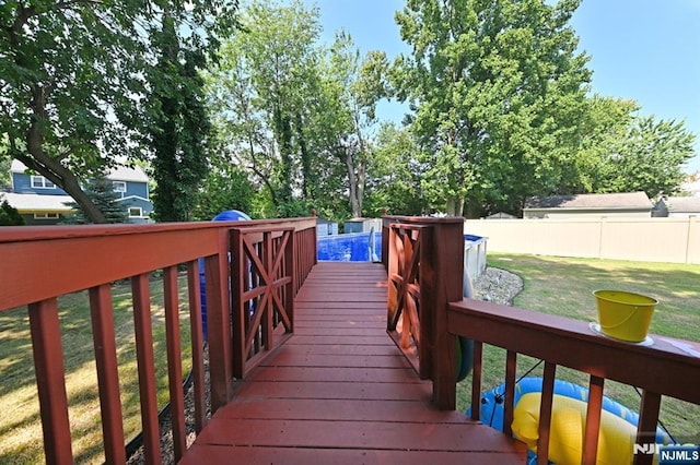 wooden deck with fence, a fenced in pool, and a yard