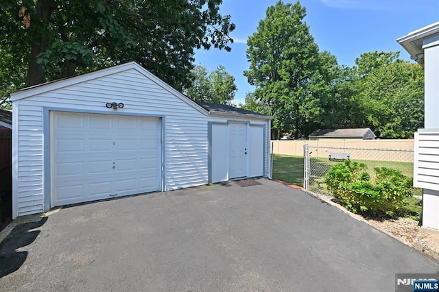 detached garage featuring fence and aphalt driveway