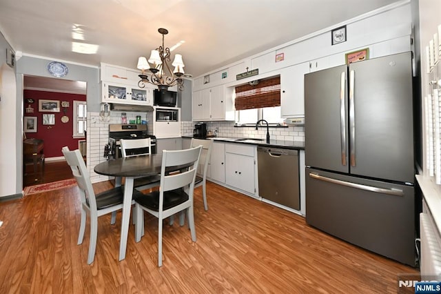 kitchen featuring dark countertops, light wood-style floors, tasteful backsplash, and appliances with stainless steel finishes