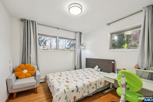 bedroom featuring baseboard heating and wood-type flooring