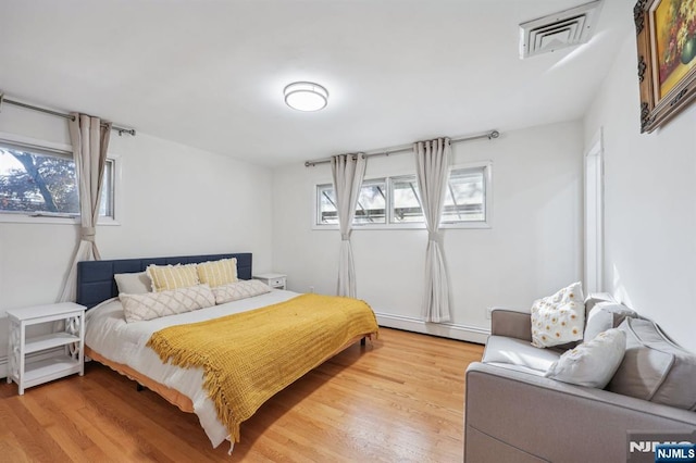 bedroom featuring baseboard heating and hardwood / wood-style floors