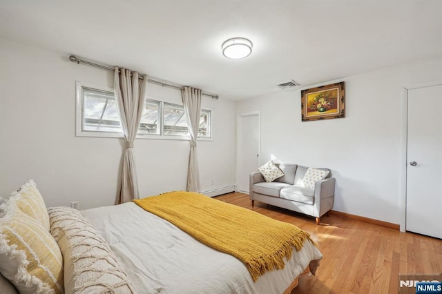 bedroom with baseboard heating and hardwood / wood-style flooring