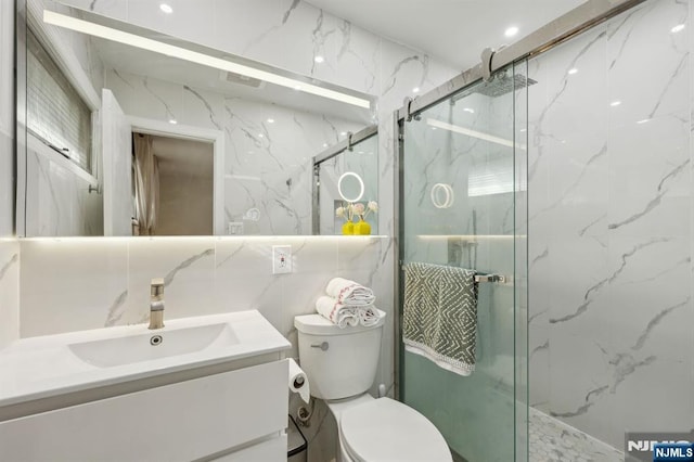 bathroom featuring tile walls, vanity, an enclosed shower, and toilet