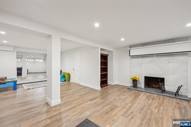 exercise area with light hardwood / wood-style flooring and a tile fireplace