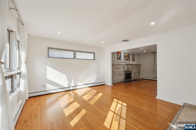 unfurnished living room featuring wood-type flooring and a baseboard radiator