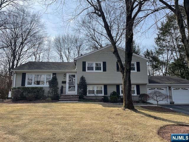 tri-level home featuring a garage, a front yard, and driveway