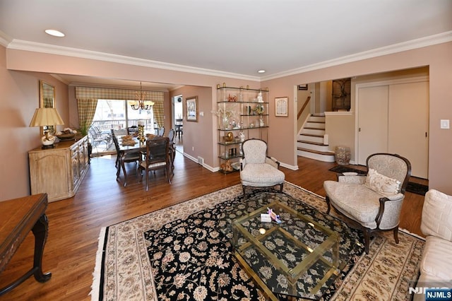 living room with a notable chandelier, wood finished floors, baseboards, ornamental molding, and stairway