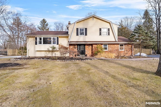 view of front of property with brick siding, a chimney, fence, and a gambrel roof