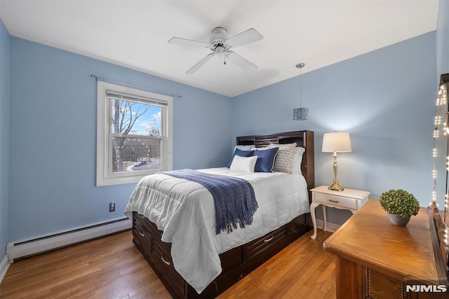 bedroom featuring a baseboard heating unit, ceiling fan, and hardwood / wood-style flooring