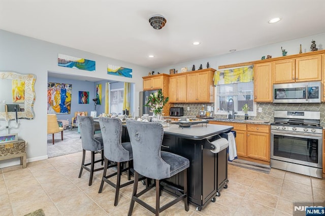 kitchen featuring stainless steel appliances, a breakfast bar, a center island, sink, and tasteful backsplash