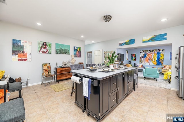 kitchen featuring stainless steel refrigerator, a kitchen breakfast bar, a kitchen island, and light tile patterned floors