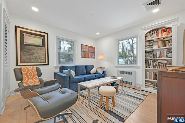 living area with light wood finished floors, radiator heating unit, visible vents, and recessed lighting